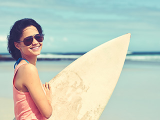 woman in sunglasses holding surf board
